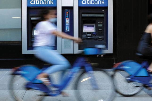 Cyclists wearing protective masks ride past a Citibank branch.