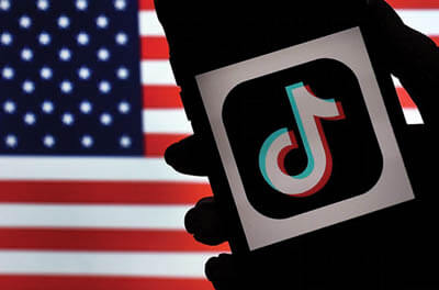 In this photo illustration, the logo for the social media app TikTok is displayed against the background of a U.S. flag on the screen of an iPhone.