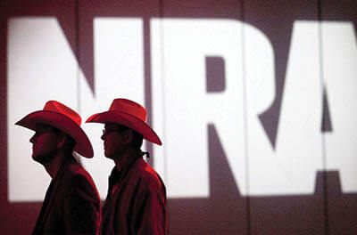 National Rifle Association members listen to speakers during its annual meeting in Houston in 2013. The NRA has been cutting staff and salaries amid the pandemic. The cuts come against the backdrop of internal turmoil, legal challenges, and a revolt among some of its members.