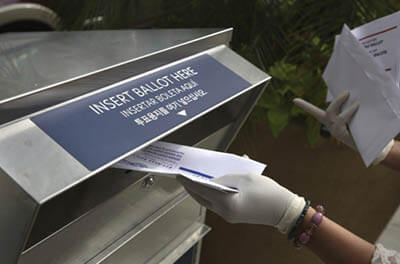 A woman deposits a mail-in ballot in a drop box in Hackensack, N.J., in July. The ability of Americans to vote by mail has become a major flash point in the 2020 election.