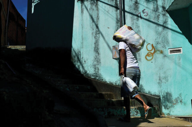 Man carries a bag of food through an impoverished borough