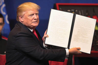 Donald Trump holds up a copy of recently signed immigration reforms