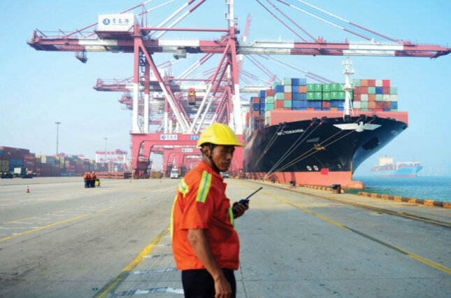 Dock worker at Chinese port stands by a large cargo ship