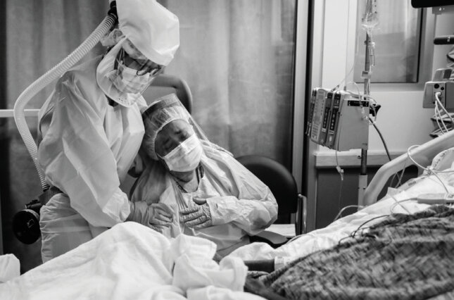 Romelia Navarro is comforted by Michele Younkin, a nurse, while sitting at the bedside of her dying husband.