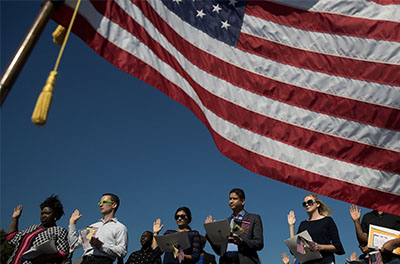 A group of new U.S. citizens standing before the flag during the playing of the national anthem