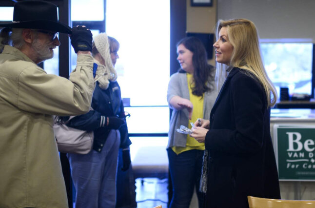 Woman in suit talks with man in cowboy hat