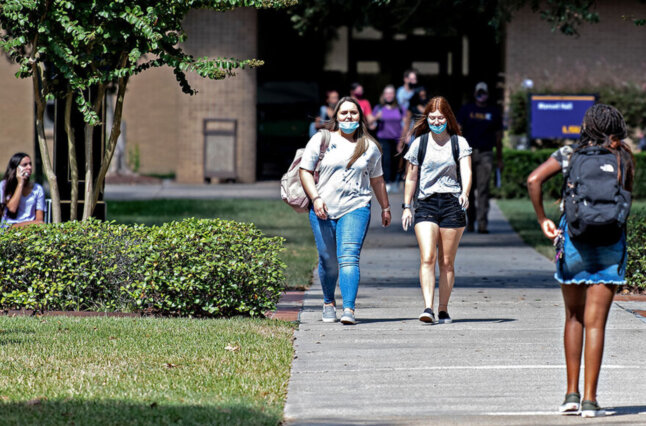 Masked College students walk through campus