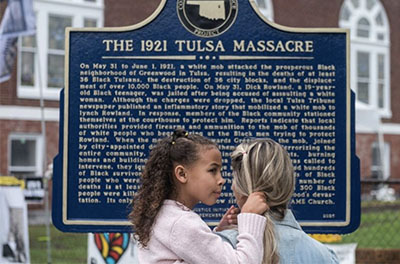 A mother and daughter stand before a historical marker for the the 1921 Tulsa Massacre