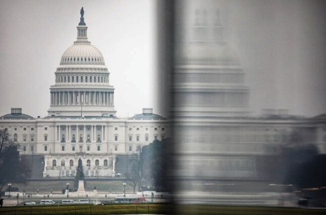 The U.S. Capitol is seen in the distance from the base of the Washington Monument on a stormy morning.