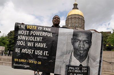 Robin Donaldson holds a banner with he voting quote and photo of John Lewis during a rally against the state's new voting restrictions outside the Georgia State Capitol, in Atlanta, Georgia, U.S., June 8, 2021