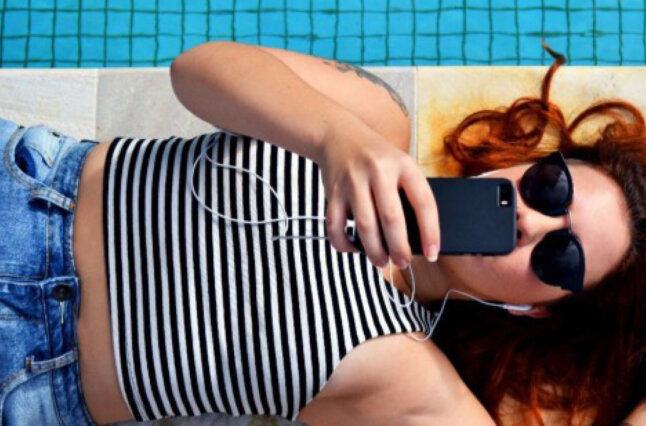 Girl sits at pool with phone