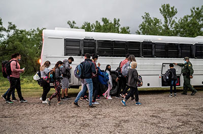 Migrants make their way toward a bus after being apprehended near the border between Mexico and the United States in Del Rio, Texas, on Sunday.