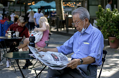 A man reads a newspaper in Bryant Park in New York City on May 19, 2021, as COVID-19 restrictions are lifted