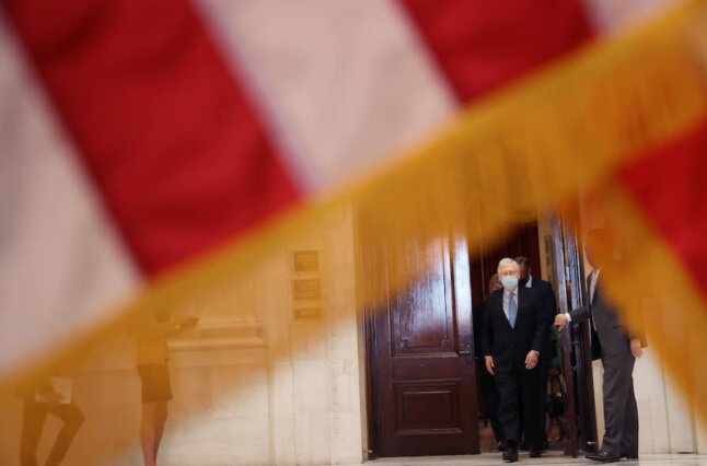 Man walks through door, flag in foreground