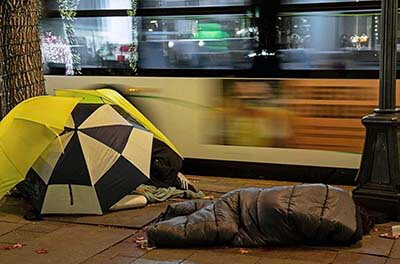 Homeless person sleeping under a blanket in Seattle