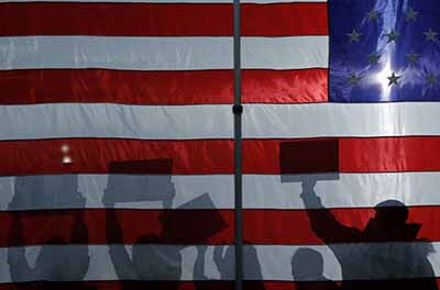 Shadow of protesters holding signs cast on an American flag