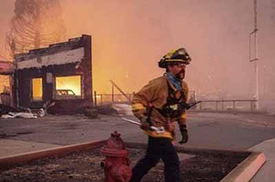 Firefighter carrying equipment near wildfires in California