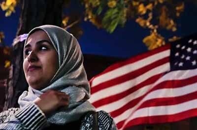 Muslim woman standing next to an American flag