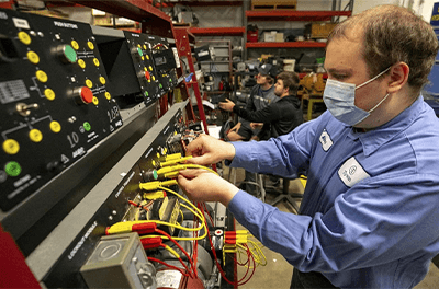 Alex Harkness changes wires on a motor controls training unit in the industrial automation lab at the Hawkeye Community College Waterloo, Iowa