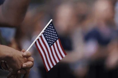 A woman holds an U.S. flag as she listens to the reading of the Declaration of Independence outside the Old State House in Boston on July 4