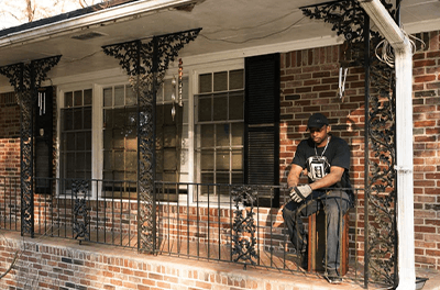 Navy veteran Prince Beatty sits on the porch of his home in the Atlanta suburb of East Point, Ga., where he faced eviction earlier this year after falling behind on his rent when it increased from $1,250 to $2,000.