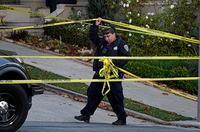 A police officer rolls out yellow tape on the closed street below the home of Paul Pelosi, the husband of House Speaker Nancy Pelosi, in San Francisco on Oct. 28