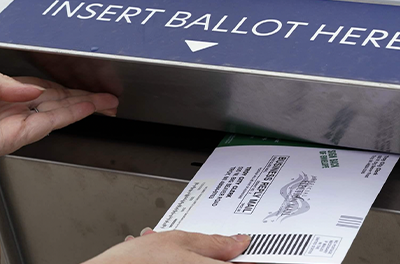 Hand placing ballon into ballot box.