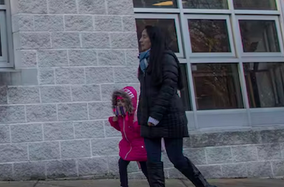 Parent walking a young girl into an elementary school.