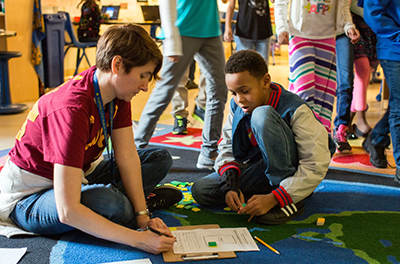 An elementary school teacher helps a young boy with a math problem.