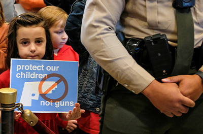 A young girl holds a sign calling for gun control amidst a crowd of demonstrators.