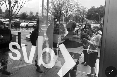 People reflected in the glass door of Silicon Valley Bank.