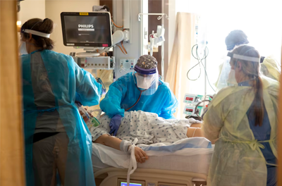 A team of nurses and physicians transfers a patient with covid-19 from the emergency room at CentraCare-St. Cloud Hospital in St. Cloud, Minn.