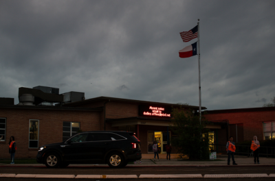 A school building with a sign over the front door stating the email address that absent notes should be sent to.